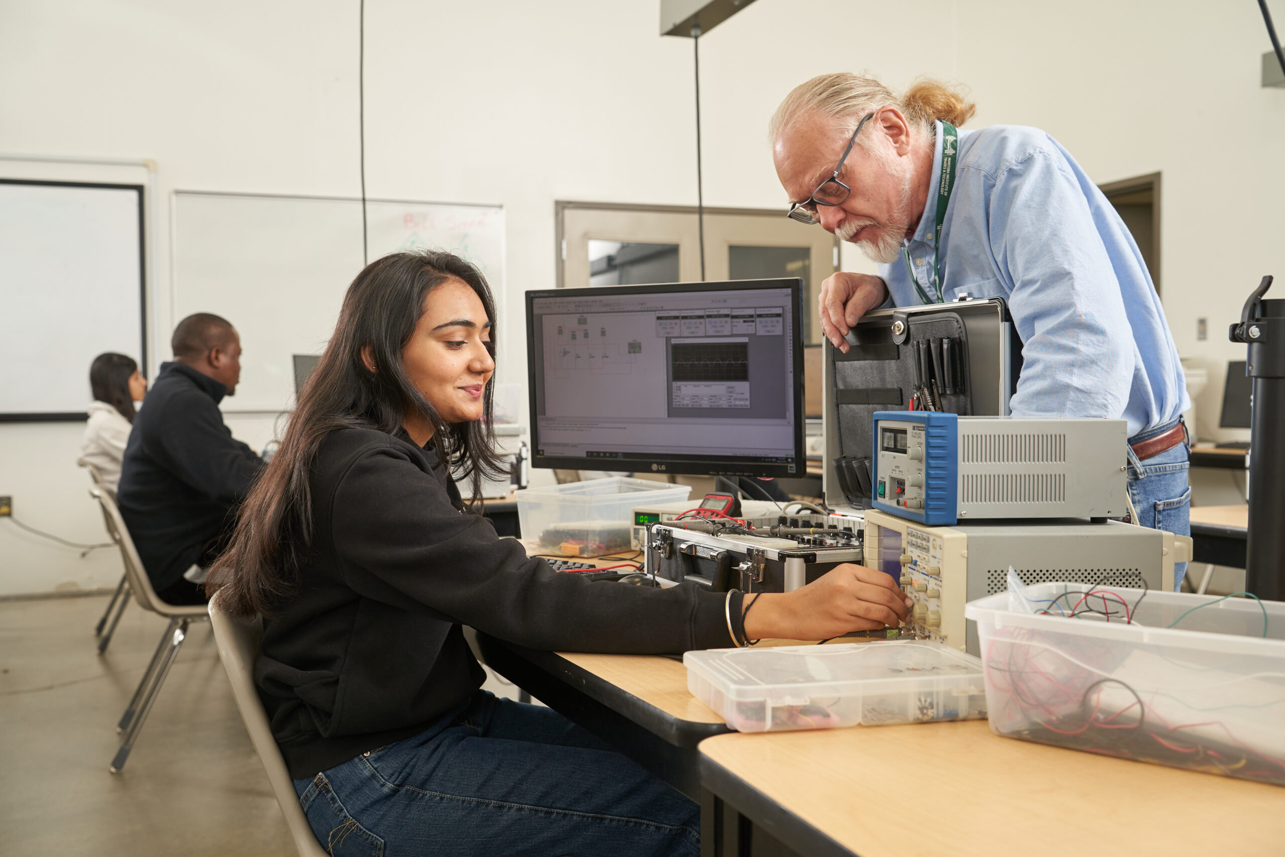 Teacher and student working in electronics classroom