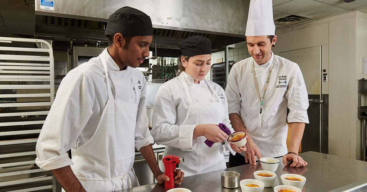 Culinary students using a small torch to make dessert