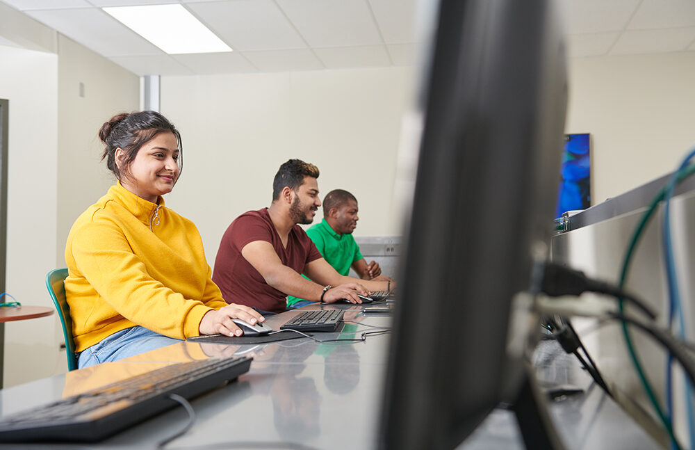 Mga mag-aaral na tumitingin sa mga screen ng computer sa isang computer lab