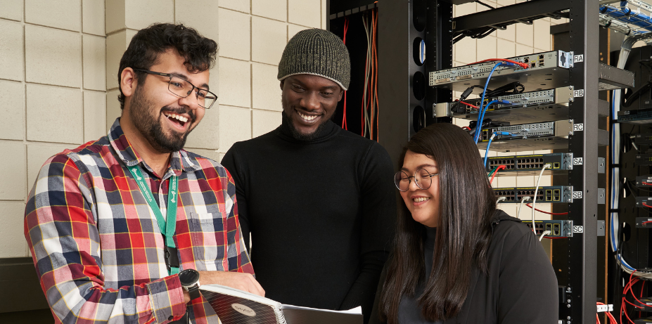 Students smiling in front of server rack