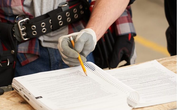 Person holding a pencil in a coil bound book