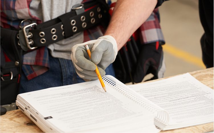 Person holding a pencil in a coil bound book