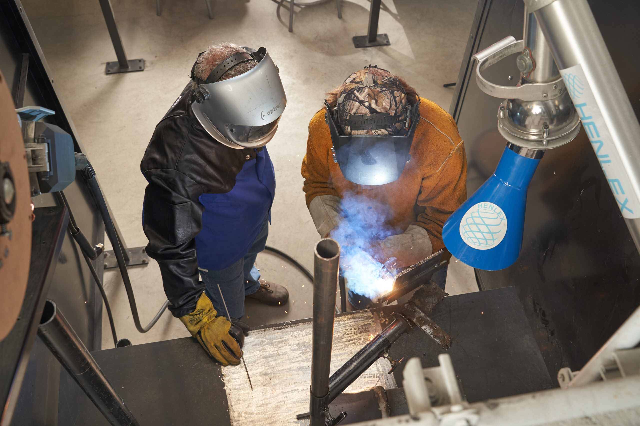 Instructor monitoring student while welding