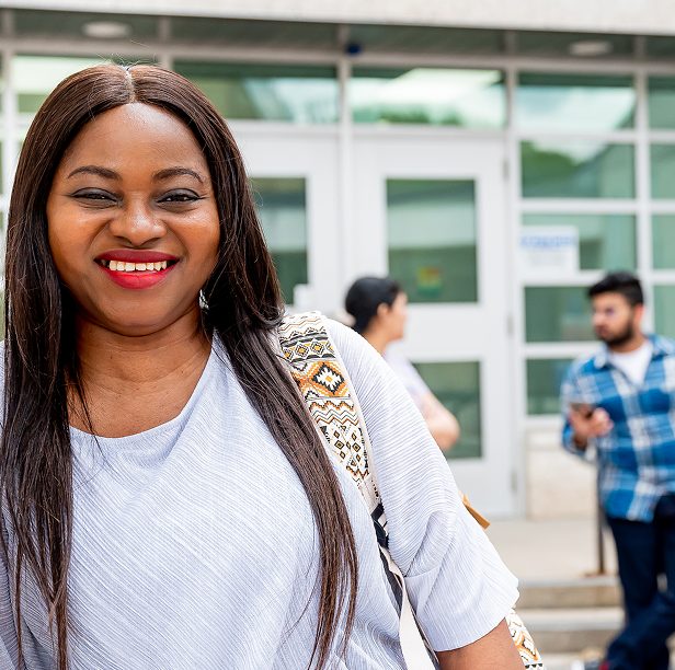 Woman smiling in front of campus