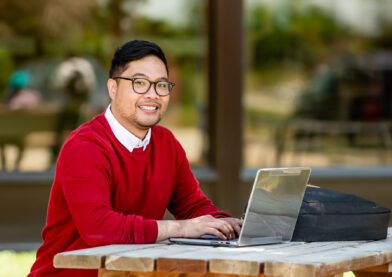 student working on a laptop on campus outdoor area