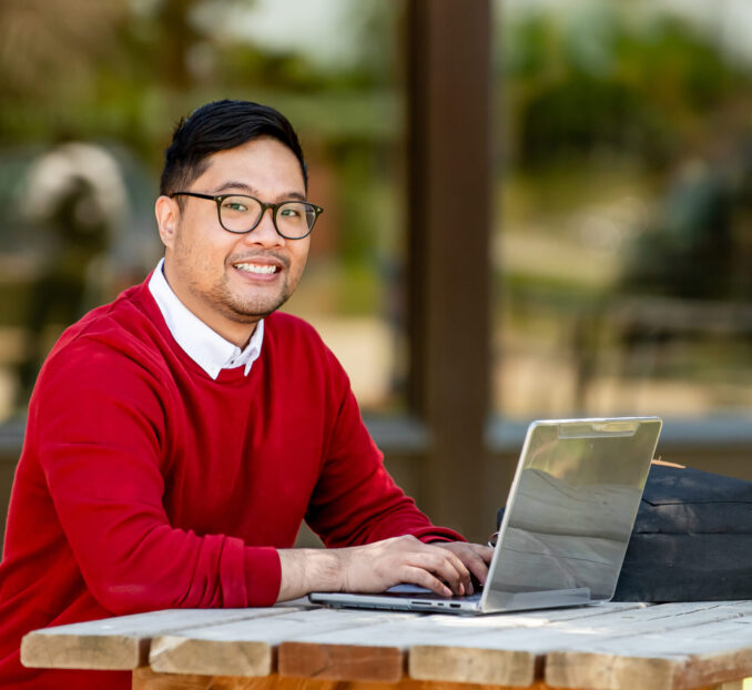 student working on a laptop on campus outdoor area