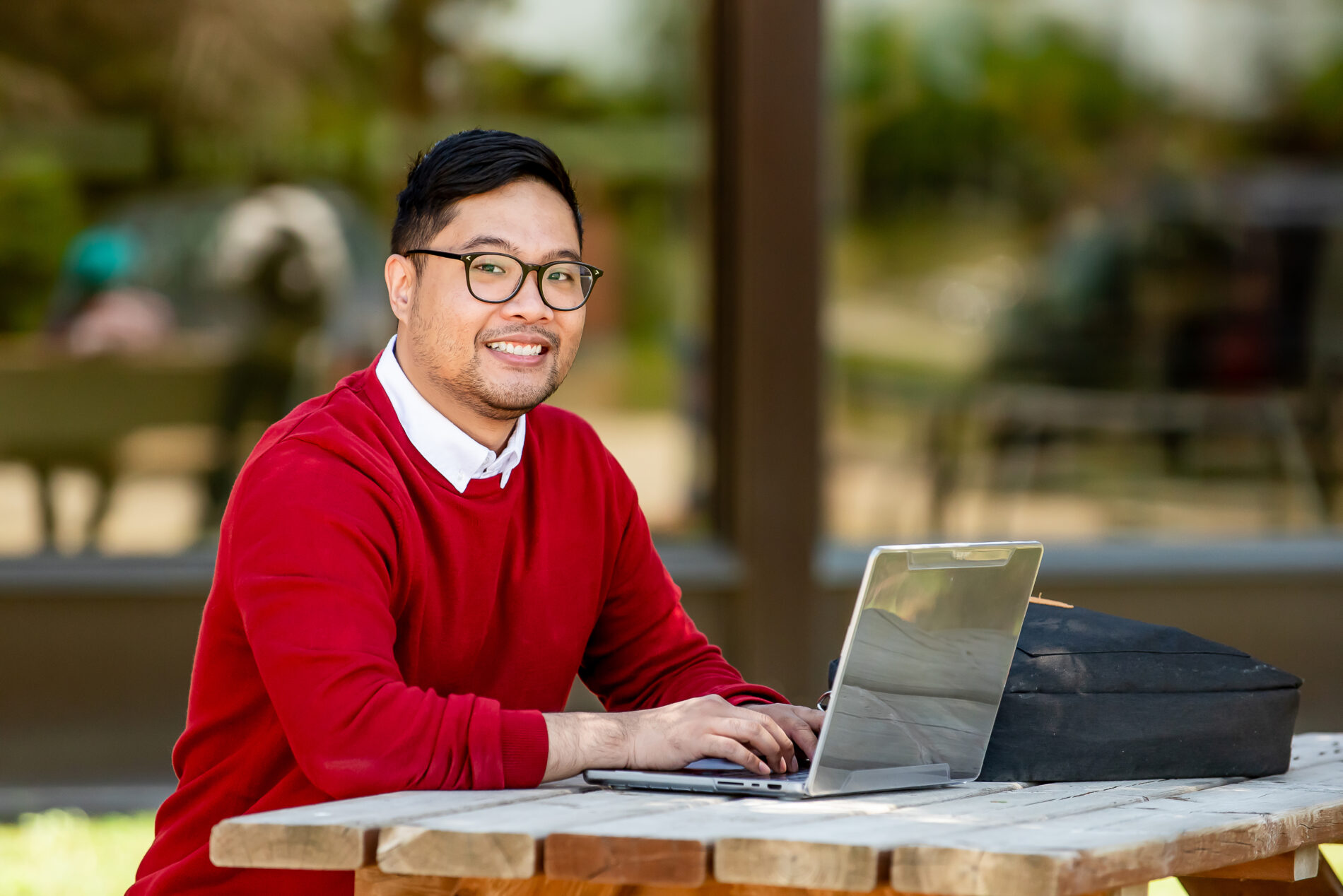 student working on a laptop on campus outdoor area