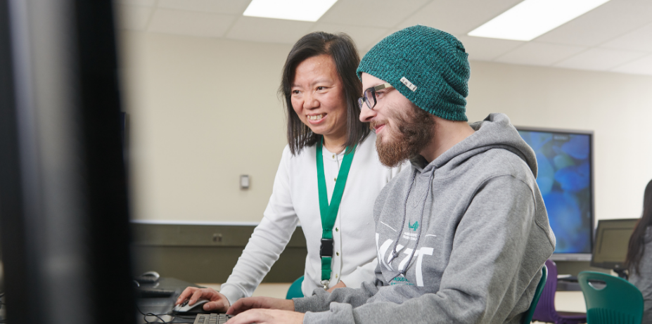 Teacher assisting student on computer