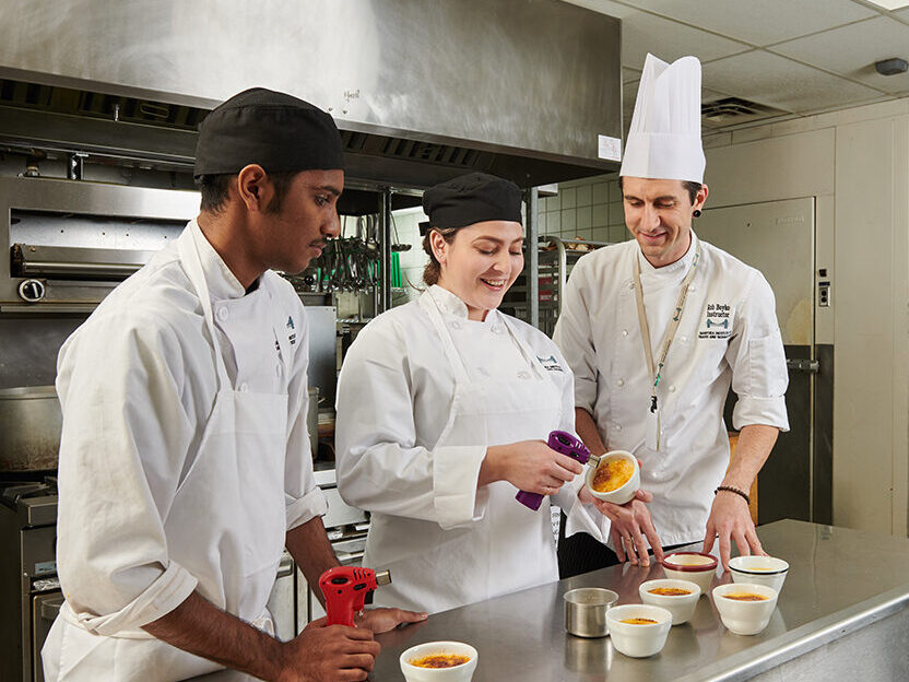 culinary student using a small torch to make dessert