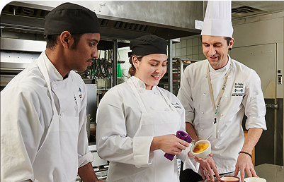 Culinary students using a torch to caramelize a brûlée