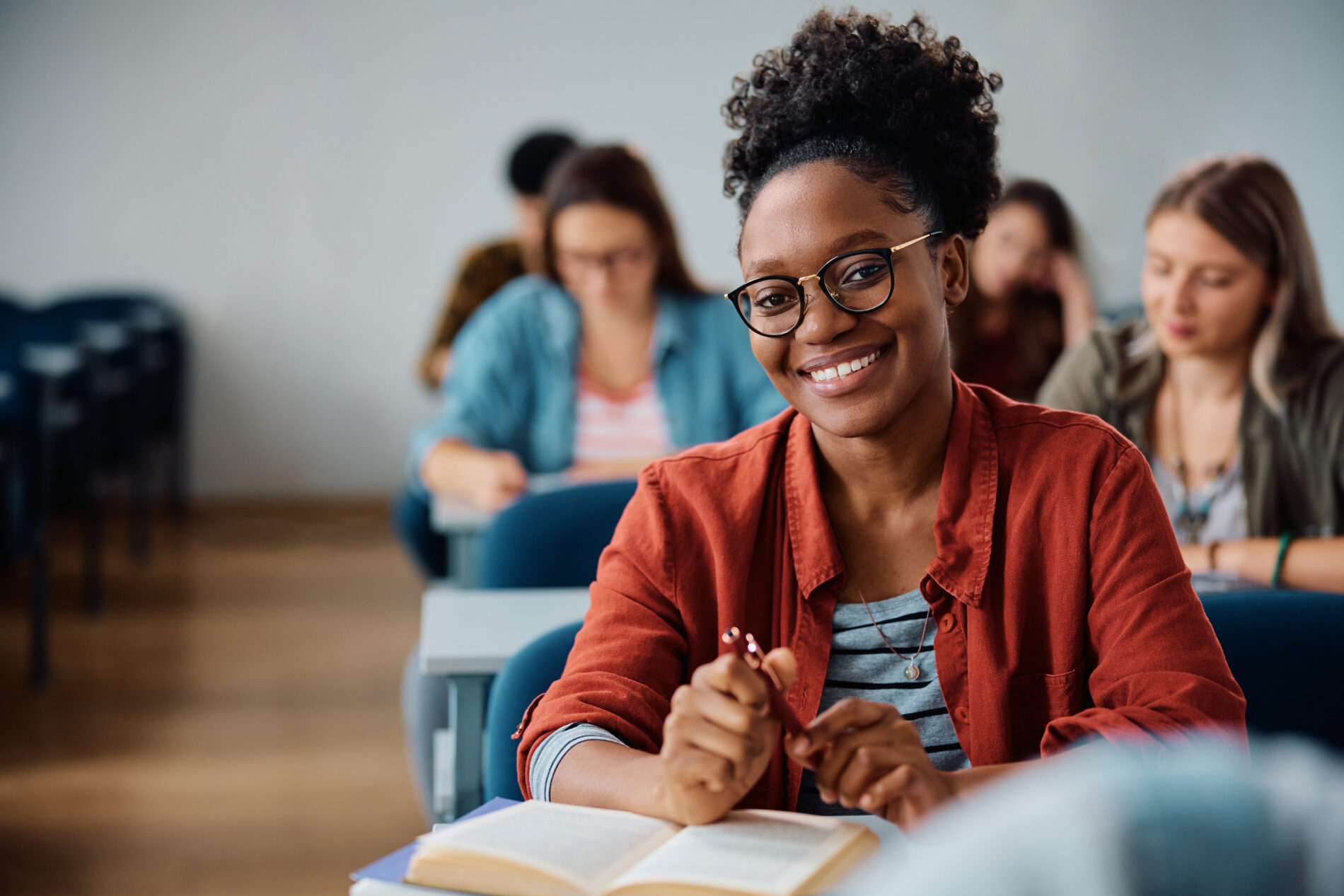 Happy female student during a class in lecture hall looking at camera.